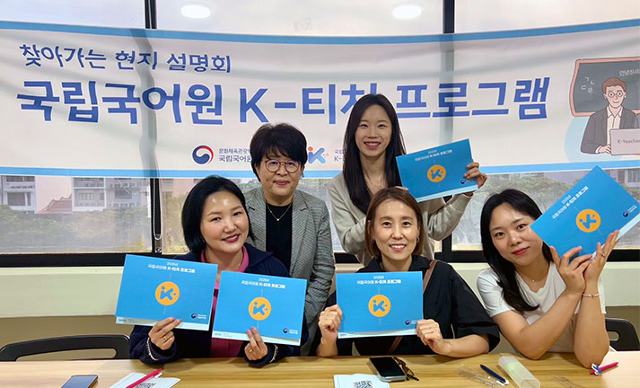 Korean teachers collaborating with South Korean professor during a teaching training program to continuously reinforce and improve study materials and oral interaction focus.